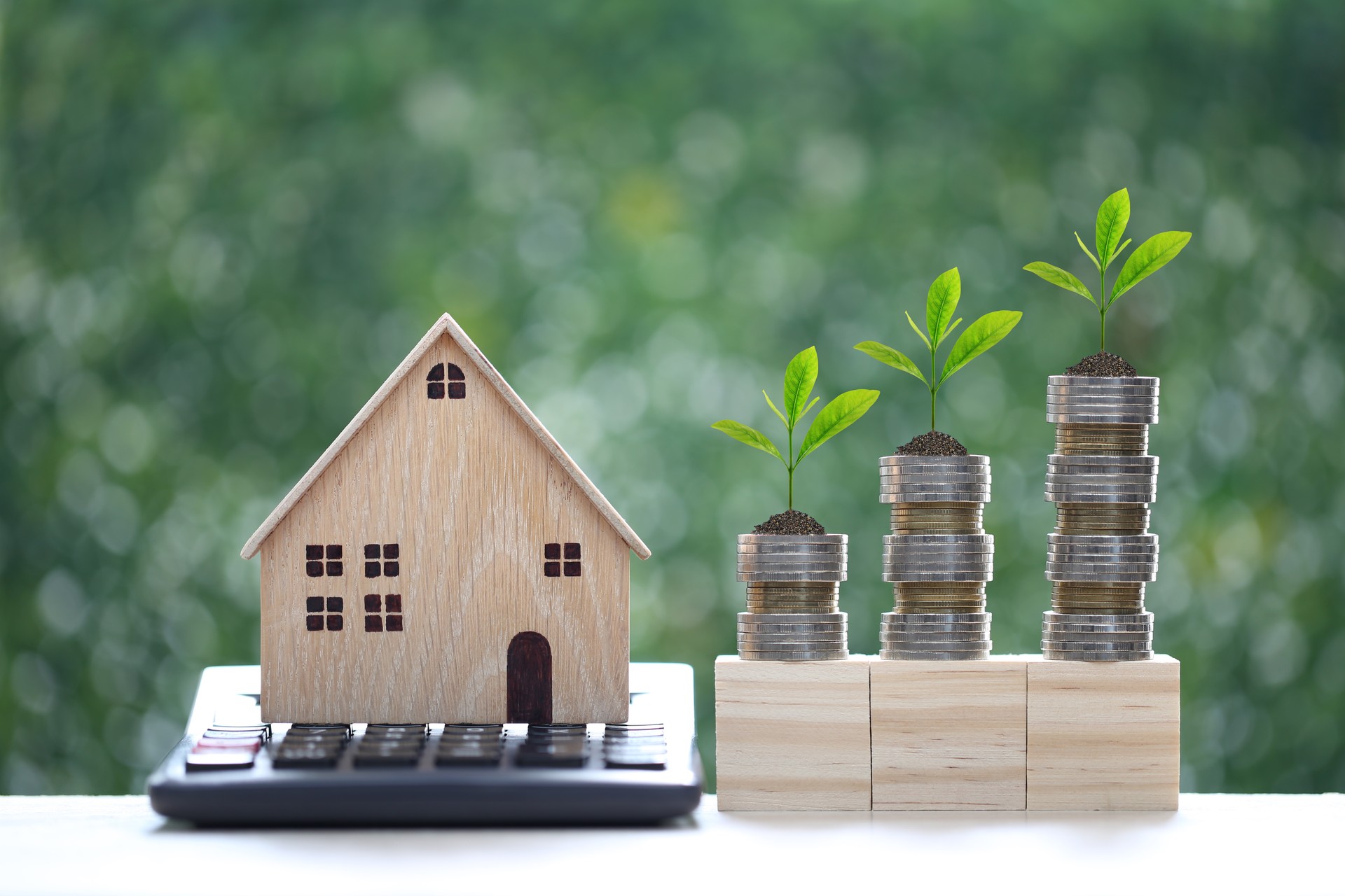 Model house on calculator with stack of coins money on natural green background, Calculating interest payments and Property tax concept