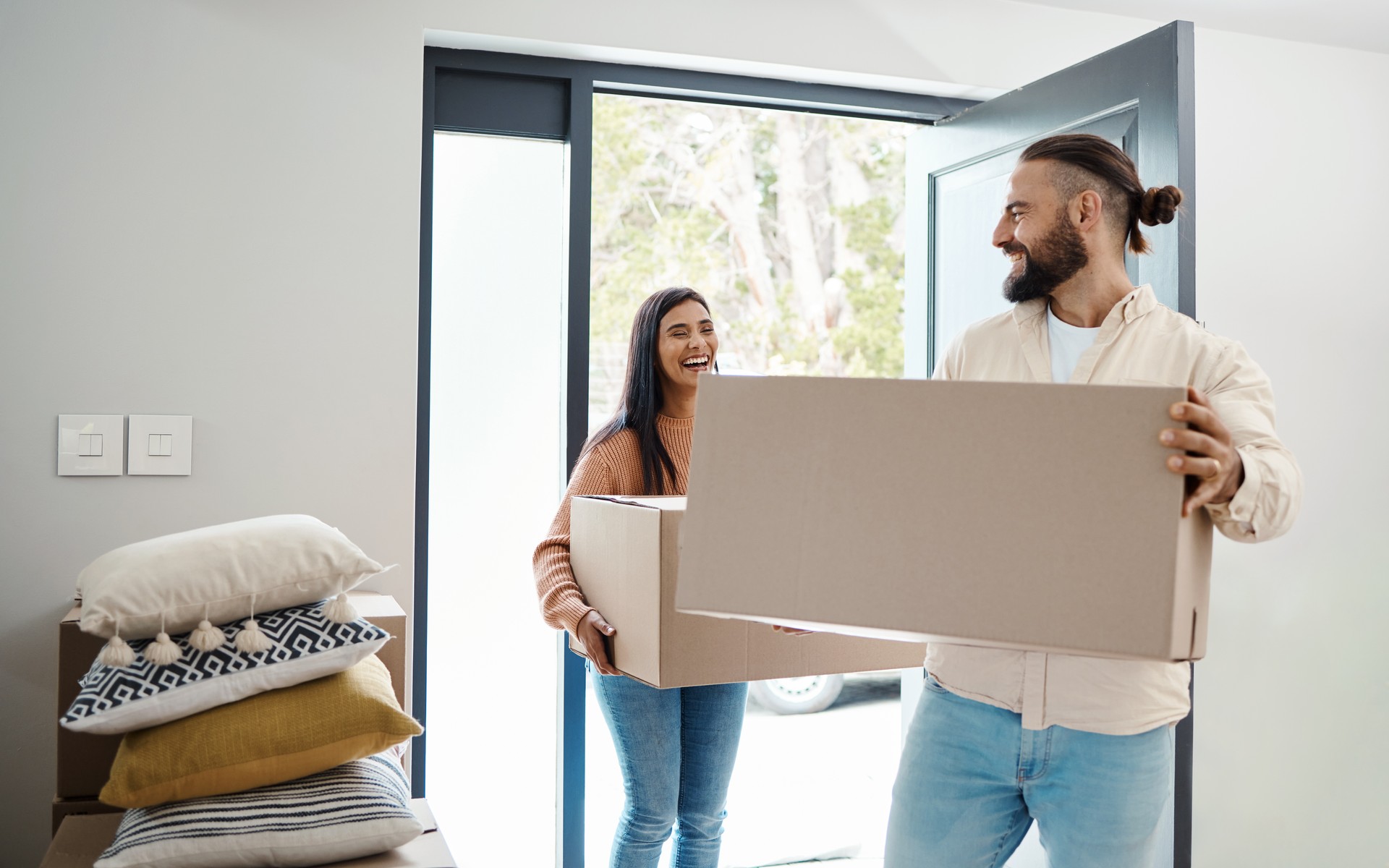 Couple moving, new house and box with happiness, man and woman, real estate property and home owner. People carrying boxes, laughing together and partnership, happy with mortgage and funny relocation